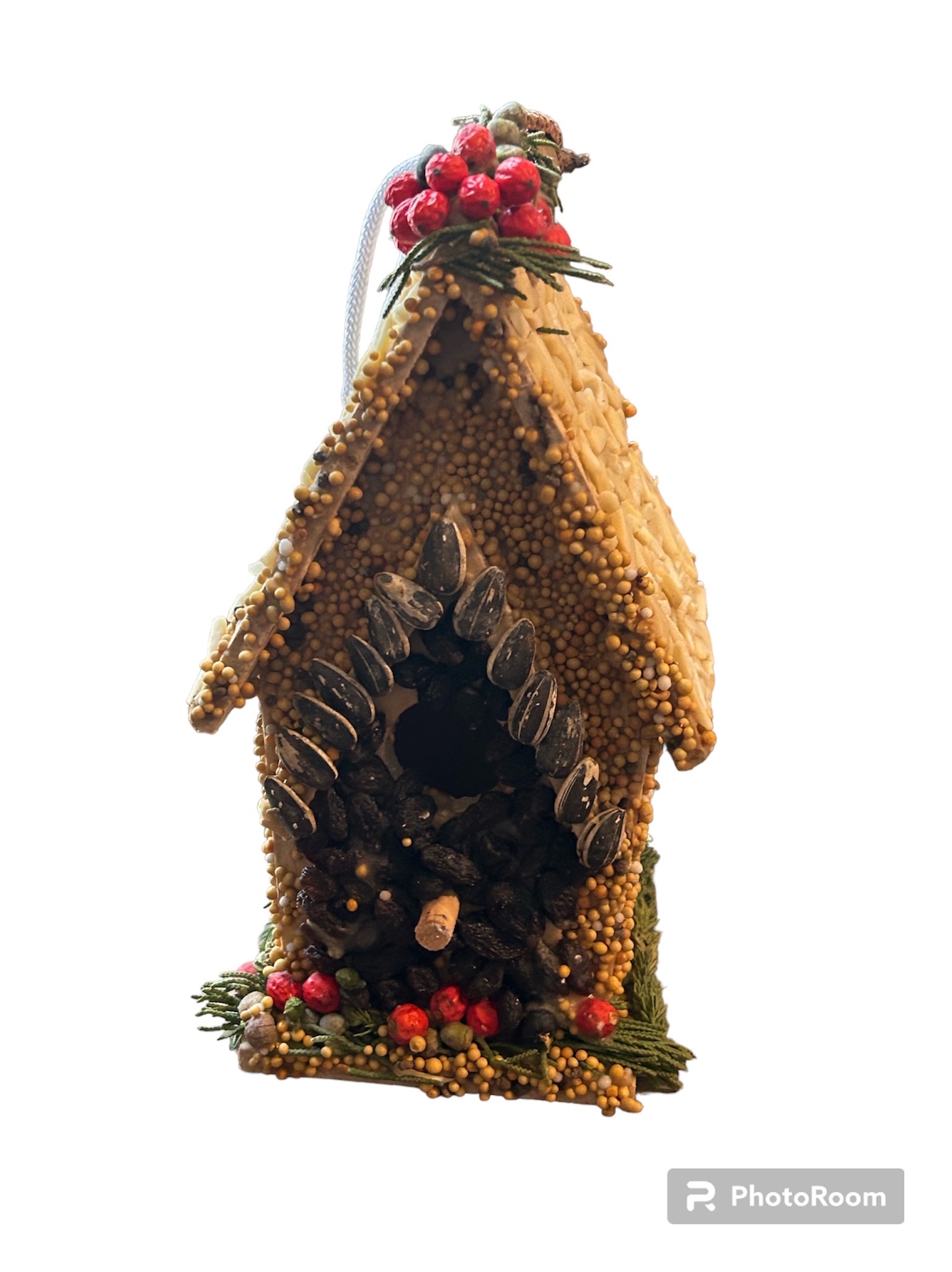 Image of a small brown birdhouse, decorated with seeds, nuts and berries