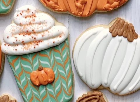 an image of fall-themed sugar cookies. Once is iced to look like a white pumpkin, while the other looks like a fall-themed beverage, with whipped cream and sprinkles on top