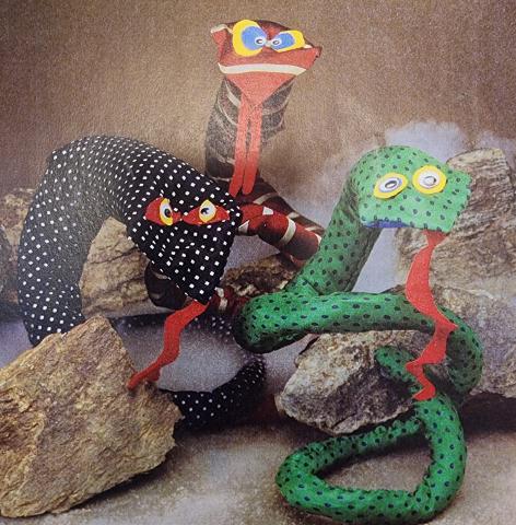 Three snakes made out of men's ties and other craft materials.