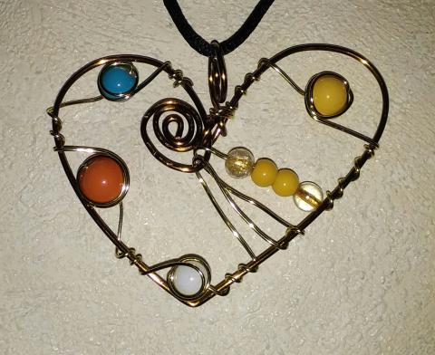 a wire pendant in the shape of a heard. there are 4 groupings of beads included in the center of the heart, and a metal swirl added towards the top