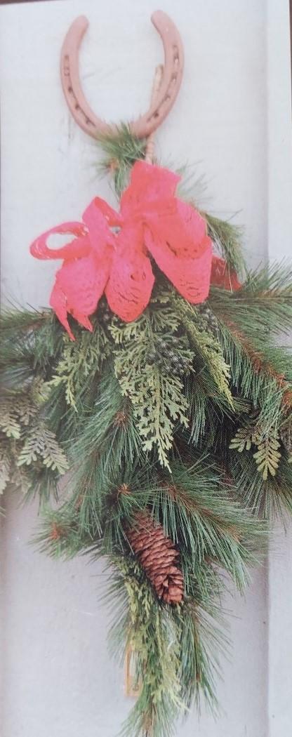 A door swag made of fresh greens, ribbon, and a lucky horseshoe. 