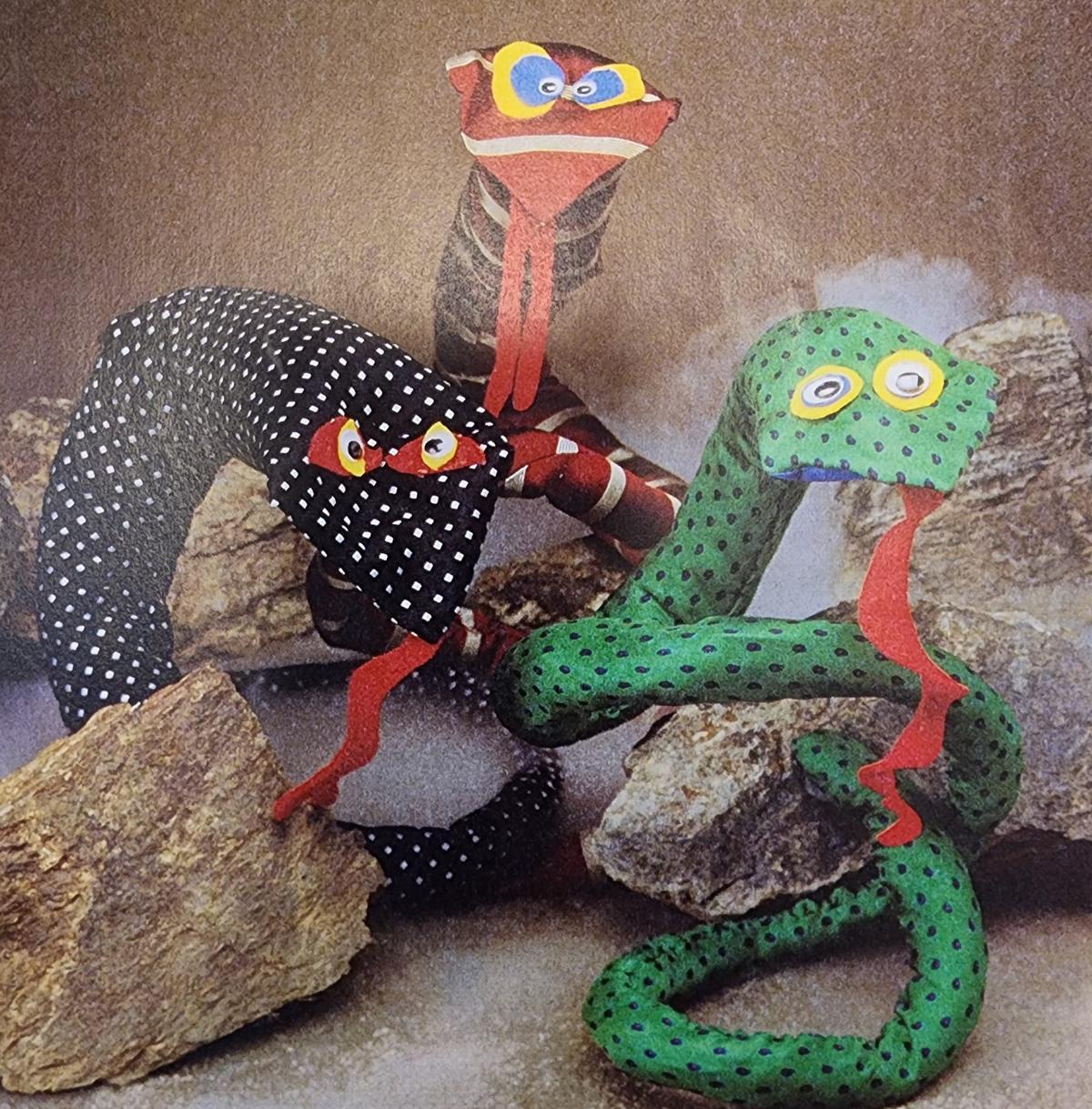 Three snakes made out of men's ties and other craft materials.